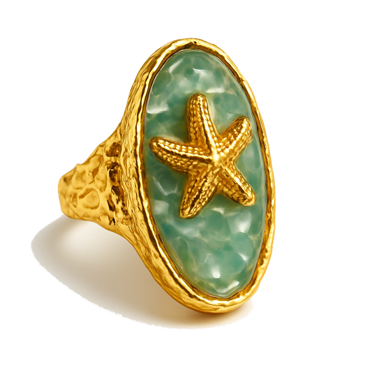 Gold ring with a starfish design on a light green stone against a white background